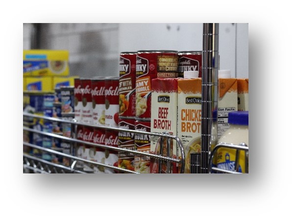 Wire shelving holding cans of soup, assorted broths, canned meats, and condiments within the UALR University District Mobile Market.